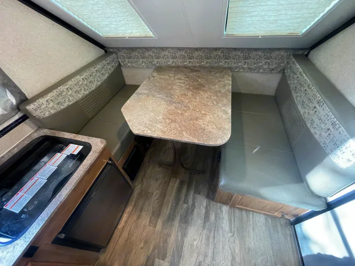 RV rental interior: U-shaped dinette with a speckled table and compact kitchen area with stove & fridge.. Forest River Flagstaff Classic 2019