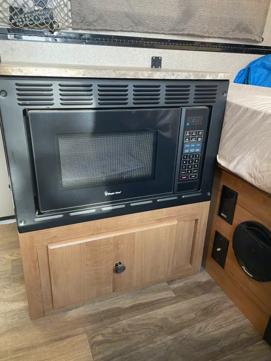 Inside an RV rental: a built-in Magic Chef microwave, wood cabinetry, and speaker, ideal for compact living spaces.. Forest River Flagstaff Classic 2019