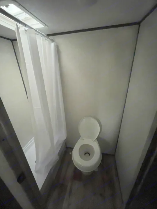 Compact RV rental bathroom. Features a white toilet, shower with curtain & skylight.. Dutchmen Aspen Trail 2023