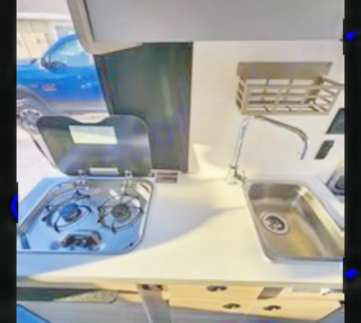 This compact RV rental kitchen features a two-burner stove, stainless steel sink, and countertop for efficient travel cooking.. Winnebago Solis 2023