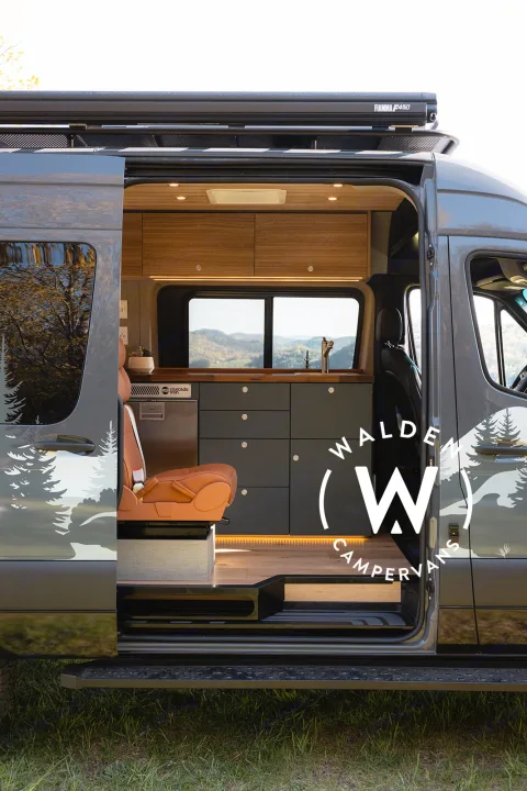 Luxury RV rental interior: custom camper van with wood accents, kitchenette, and scenic views through the open side door.. Mercedes-Benz Sprinter 2023
