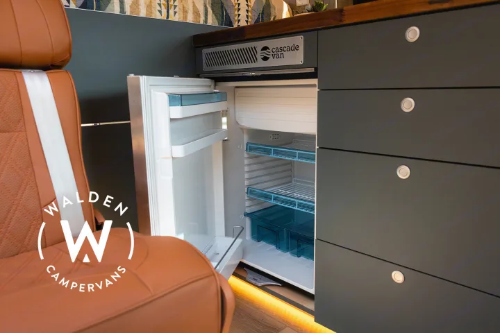 RV rental: Campervan interior with open compact fridge, blue shelves, comfy seat, & dark storage drawers.. Mercedes-Benz Sprinter 2023