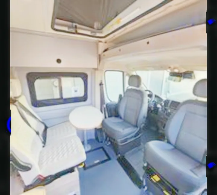Spacious RV rental interior showing swiveling driver seats, passenger bench, & small table. Perfect for your next road trip adventure.. Winnebago Solis 2023