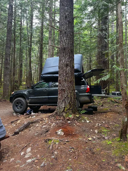 Forest camping setup: SUV with open rooftop tent & Dometic fridge. An ideal alternative to an RV rental for off-grid adventure.. Toyota 4runner 2006