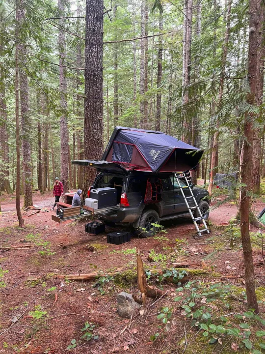 Forest campsite with an SUV featuring a rooftop tent & pull-out kitchen. A versatile option for your next outdoor RV rental adventure.. Toyota 4runner 2006