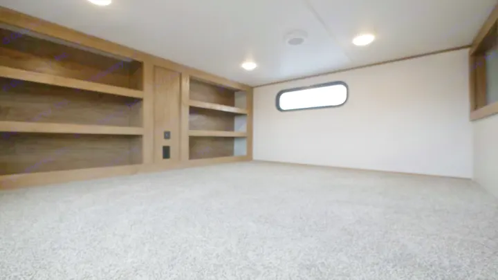 RV rental interior: cozy bunk/loft space with light grey carpet, built-in wooden shelves, and an oblong window.. Forest River Sabre 2021
