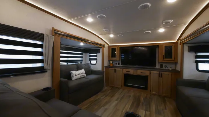Spacious rv rental living room featuring comfortable seating, a large TV, and an electric fireplace.. Forest River Sabre 2021