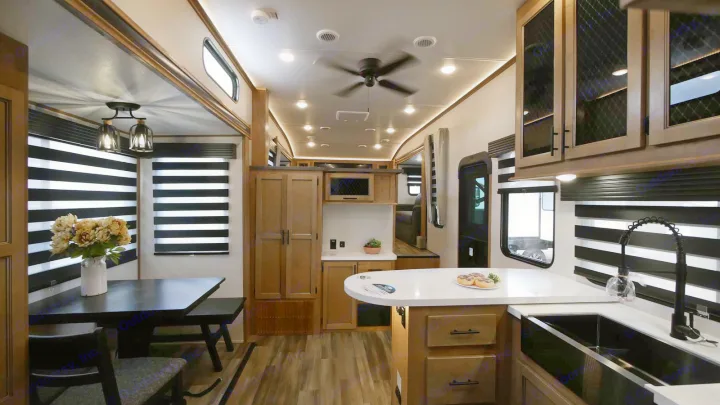 Spacious RV rental interior: kitchen island, dining table, wood cabinets, and modern blinds.. Forest River Sabre 2021