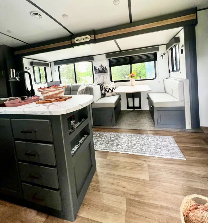 Cozy, modern RV rental interior featuring a kitchen island, dining booth, and large windows with scenic views.. Keystone Bullet Ultra Lite 2023