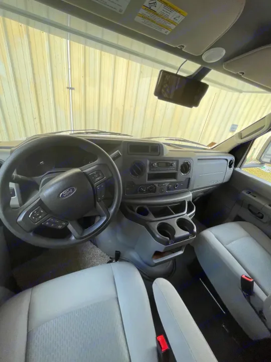 Inside an RV rental: Driver's view of the Ford cockpit, including the steering wheel, dashboard, and light gray front seats.. Forest River Sunseeker 2021