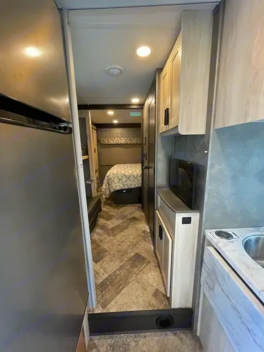 This RV rental features a modern interior: compact kitchen, cozy bedroom, and bright living space, perfect for your next adventure.. Forest River Sunseeker 2021