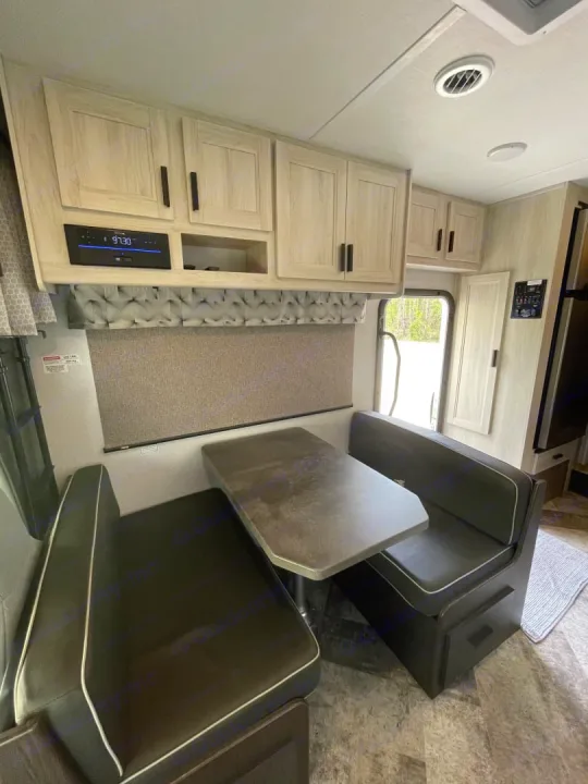 Spacious RV rental interior featuring a modern dinette area with dark seating, light wood cabinets, and an entertainment system.. Forest River Sunseeker 2021