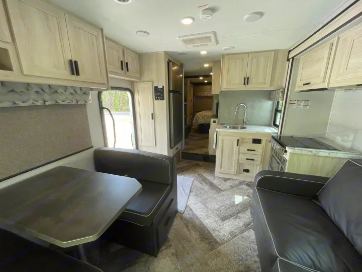 Inside this RV rental: a modern kitchen, cozy dinette, sofa, and bedroom access. Perfect for your next adventure.. Forest River Sunseeker 2021