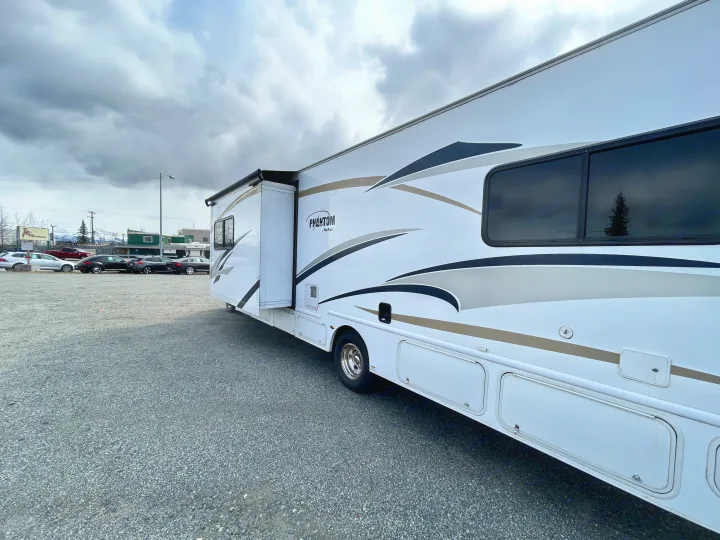 White Phantom by Nexus RV rental parked on a gravel lot with its slide-out extended. Ready for your next road trip adventure.. Nexus Phantom 2018