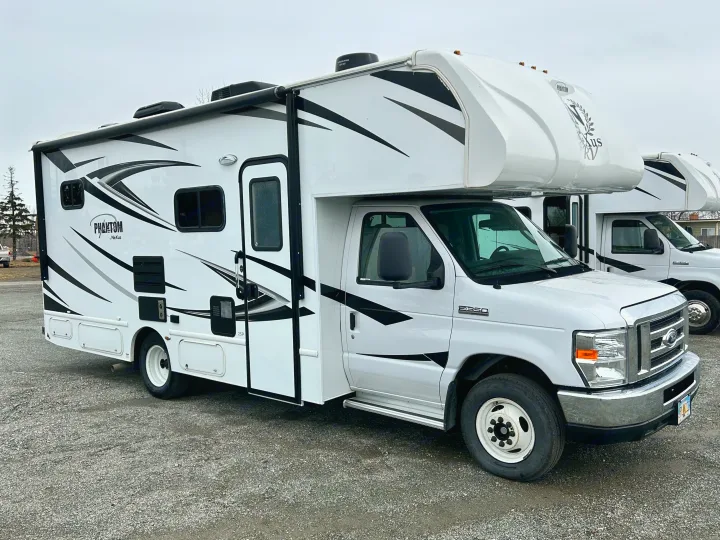 White Class C RV rental, with black and grey graphics, parked on a gravel lot.. Nexus Phantom 2020