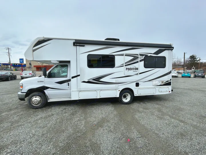 White NeXus Phantom RV with black & gray graphics, parked on gravel. Great for your next RV rental trip.. Nexus Phantom 2020