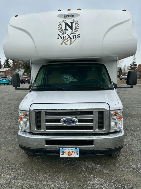 Front view of a white Nexus Phantom Class C rv rental on a Ford chassis in Alaska, parked on gravel.. Nexus Phantom 2020