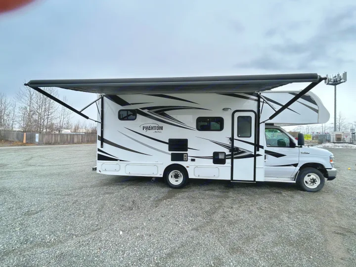 White Phantom Class C RV rental with extended awning on a gravel lot.. Nexus Phantom 2020