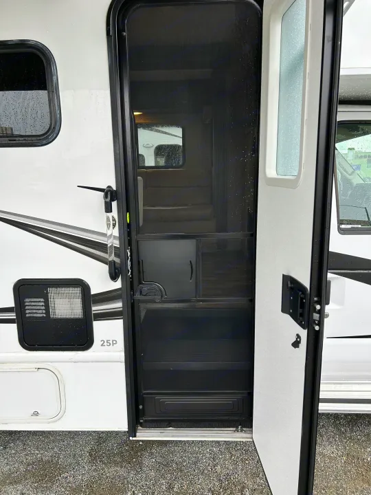 RV rental: Open motorhome entrance with screen door, revealing steps and interior. Wet white exterior on gravel.. Nexus Phantom 2020