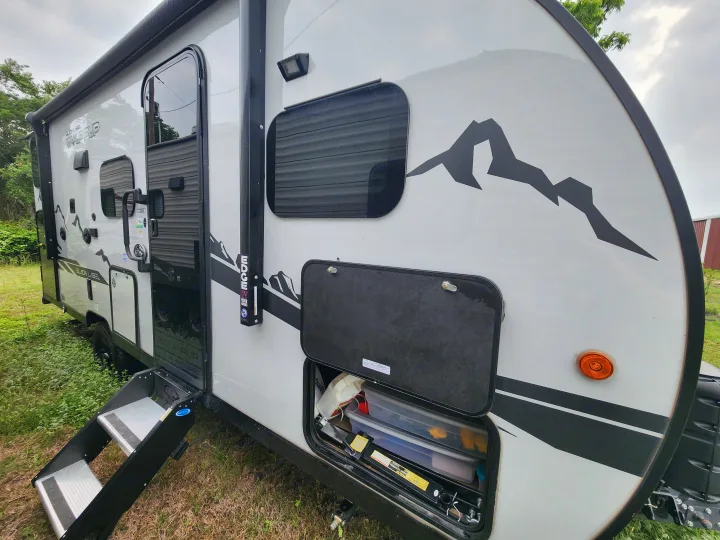 This white Wolf Pup travel trailer, perfect for an rv rental adventure, features deployed steps and accessible exterior storage.. Forest River Cherokee Wolf Pup Black Label 2022