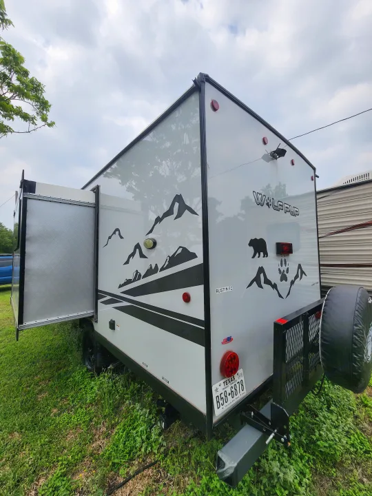 Grey Wildwood travel trailer RV rental with rear ramp, black mountain graphics & bear, and Texas plate. Great for adventures!. Forest River Cherokee Wolf Pup Black Label 2022