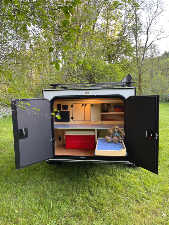 Open rear galley of a compact rv rental camper, revealing kitchen, cooler, & storage for outdoor trips.. Aero Build Burnside 2023