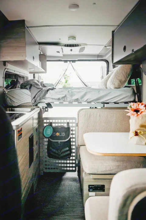 Cozy RV rental interior with a raised bed, kitchen, and dinette. Perfect for road trips and adventurous travel.. Winnebago Solis Pocket 2022