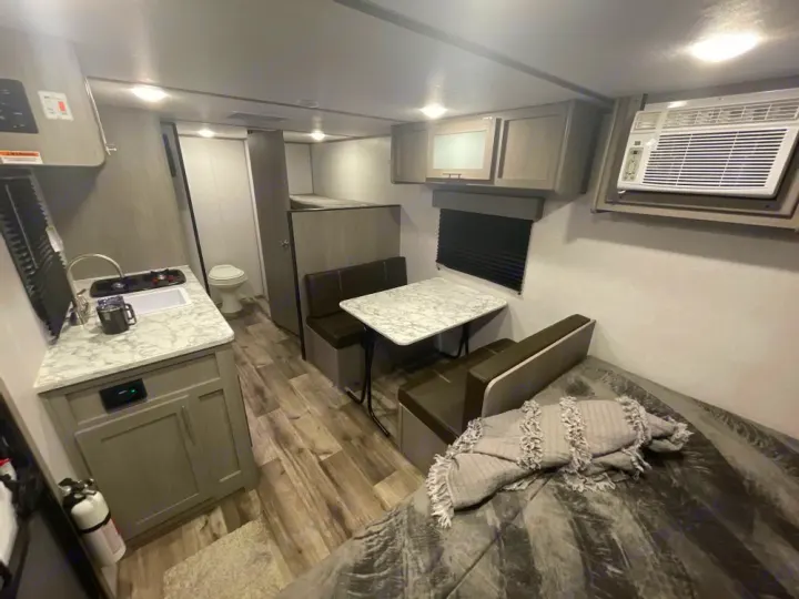 An RV rental's compact interior showing kitchen, dining, bunk/toilet area, and bed. Ideal for travel accommodation.. Coleman Other 2022