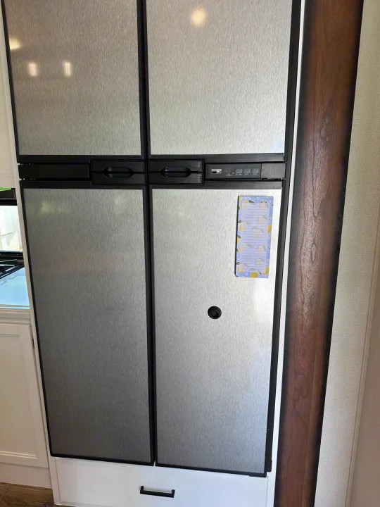 Stainless steel Norcold refrigerator with black trim and a control panel, typical in an RV rental.. Crusader Crusader Fifth Wheel 2022