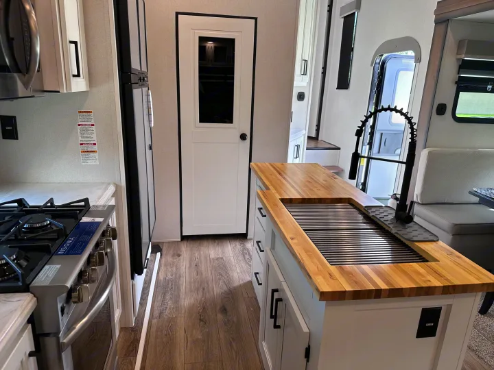Stylish RV rental kitchen interior with butcher block counter, sink, gas stove, and white cabinets.. Crusader Crusader Fifth Wheel 2022