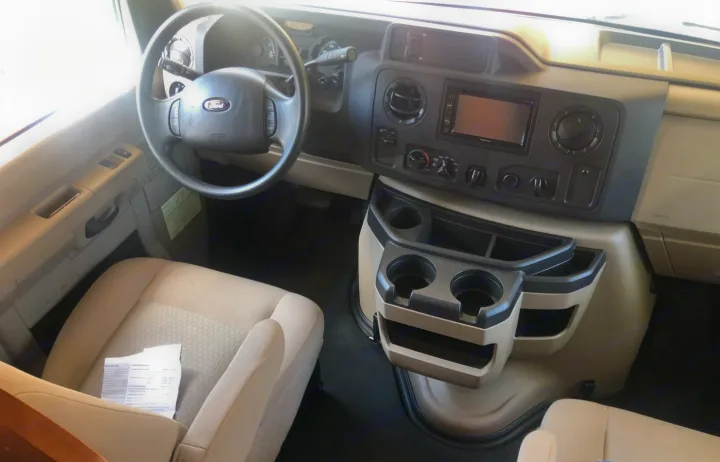 RV rental interior view: spacious cockpit with Ford steering wheel, dashboard, and convenient cup holders.. Winnebago Minnie Winnie 2016