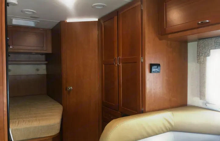 RV rental interior featuring bunk beds, light wood cabinets, a thermostat, and comfortable seating.. Winnebago Minnie Winnie 2016