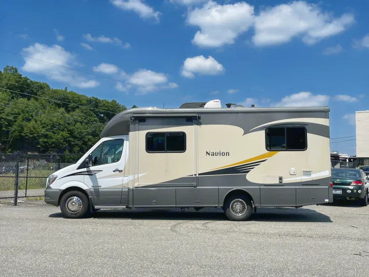 This modern Navion RV rental, a Sprinter motorhome, is parked, gleaming under a sunny sky, ready for adventure.. Itasca Navion 2015