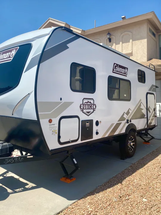 Bright white Coleman Rubicon RV rental, set up on a driveway for a sunny day's viewing, ready for travel adventures.. Dutchmen Coleman Rubicon 2022