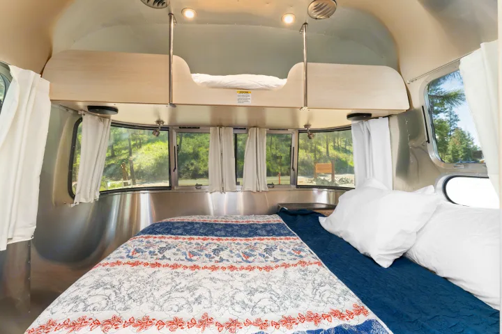 Cozy Airstream RV rental bedroom with lower bed and bunk, ideal for travelers seeking comfortable accommodations amidst nature.. Airstream Flying Cloud 2023