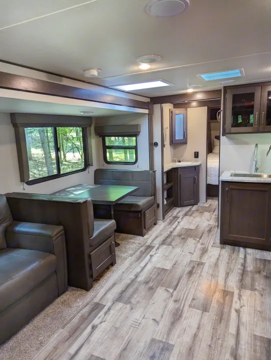 Spacious RV rental interior featuring a modern dinette, sofa, kitchen, and bedroom area.. Grand Design Transcend Xplor 2022