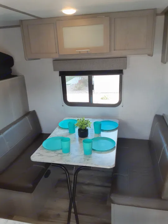 Inside an rv rental: inviting dinette with marbled table, blue dishes, and built-in storage.. Coleman Other 2022