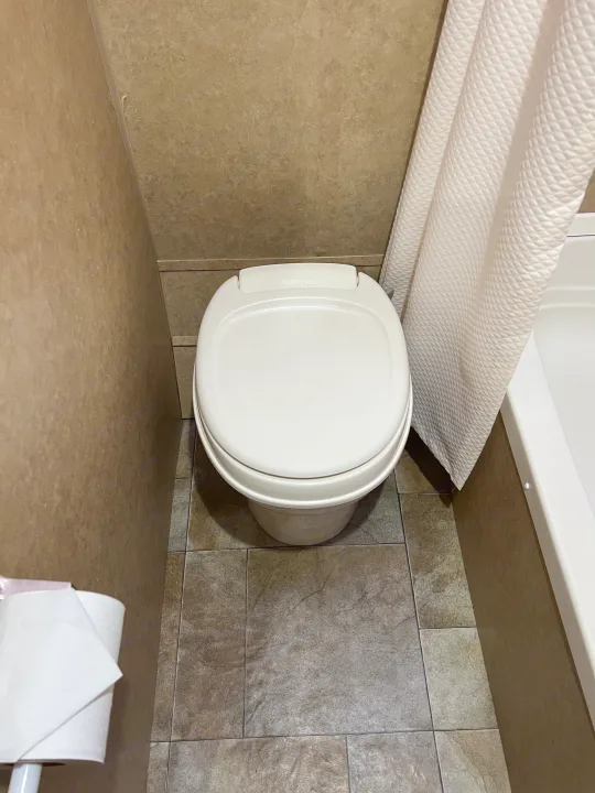 Compact bathroom in an rv rental, featuring a Thetford toilet, tiled floor, and shower curtain.. Jayco Jay Flight Swift 154 BH Slx 2013