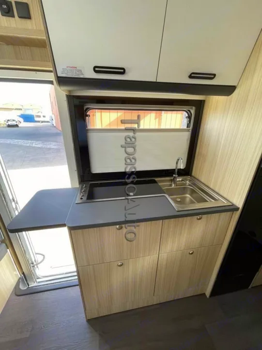 An RV rental's compact kitchen area is shown, featuring a sink, stovetop, and overhead and lower cabinets for storage.. SunLiving A 75 DP 2024