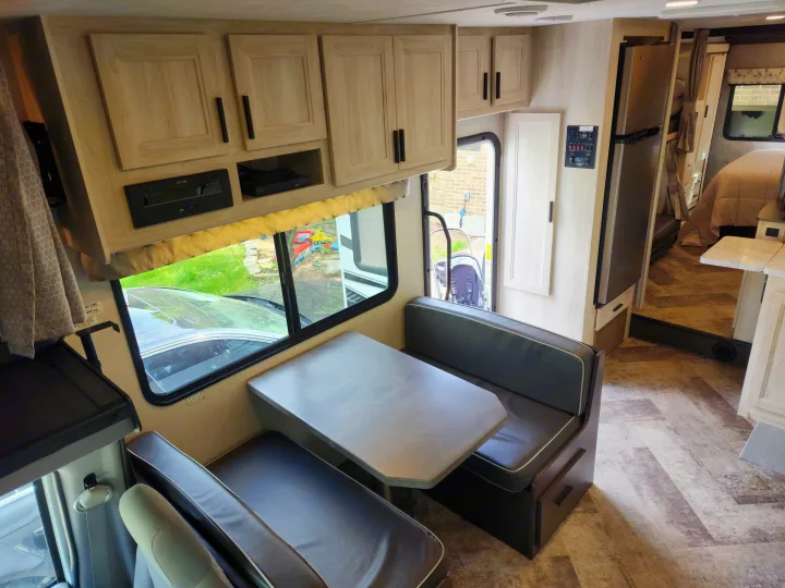 Comfortable RV rental interior: dinette, overhead storage, refrigerator, and bedroom visible. Ideal for family adventures.. Forest River Sunseeker LE 2021