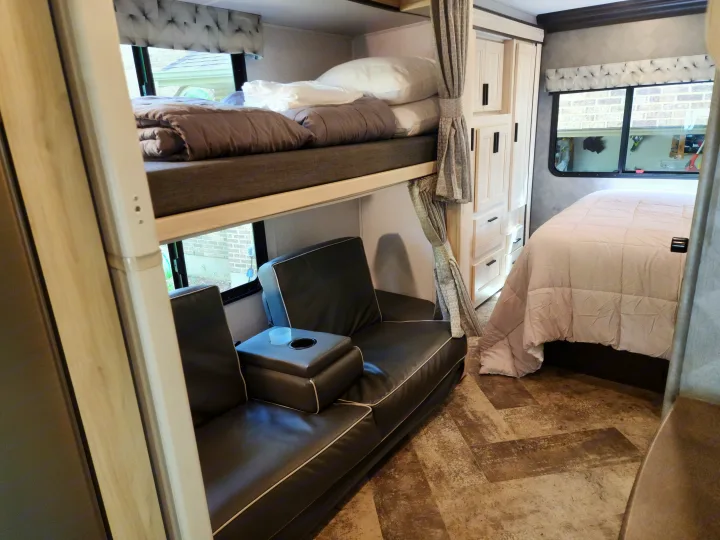 Inside this modern RV rental: cozy bunk beds, a comfy sofa with cupholders, and a spacious master bed area with storage cabinets.. Forest River Sunseeker LE 2021