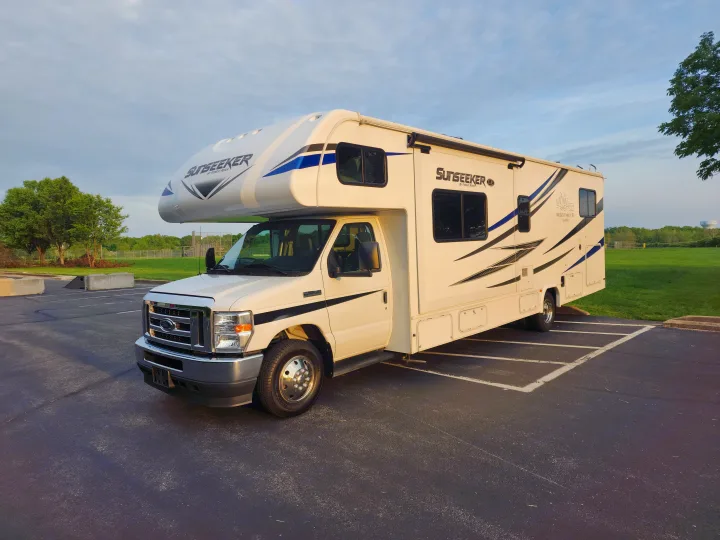 This white Sunseeker Class C RV rental by Forest River is parked on asphalt with green surroundings.. Forest River Sunseeker LE 2021
