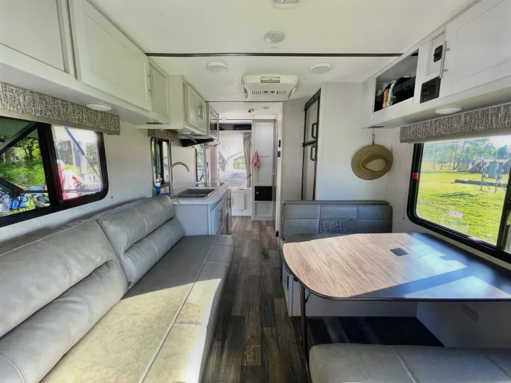Bright, modern RV rental interior featuring a kitchen, sofa, and dinette. Ideal for your next camper journey.. Keystone RV Bullet Crossfire 2019