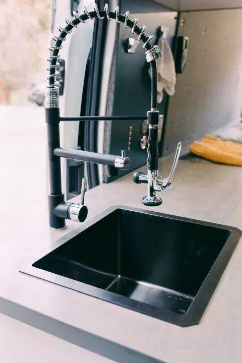 Modern RV rental kitchen featuring a sleek black sink and two sophisticated faucets, perfect for compact living.. Ford Transit 250 RWD 2018