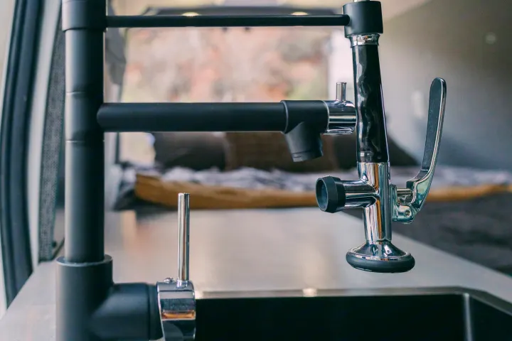 Sleek black and chrome kitchen faucet & water tap over a sink in an RV rental. Modern amenities for comfortable travels.. Ford Transit 250 RWD 2018