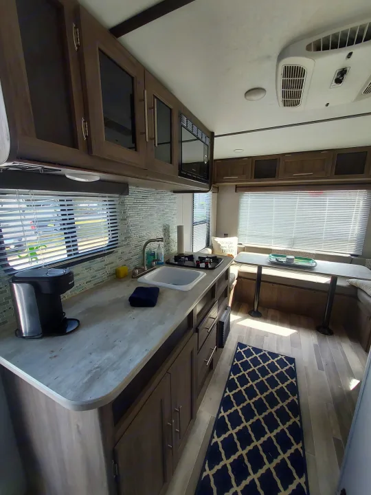 An RV rental interior showcasing a modern kitchen, dinette, overhead cabinets, and AC unit for comfortable travels.. Crossroads RV Zinger Lite 2022