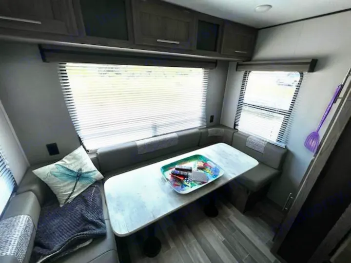 Cozy RV rental interior: dinette area with U-shaped seating, table, windows, and overhead cabinets for comfortable travel.. Crossroads RV Zinger Lite 2022