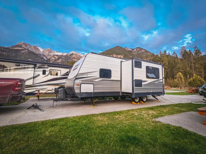 An RV rental travel trailer is set up at a beautiful mountain campground, with a motorhome & truck nearby for outdoor enthusiasts.. Coleman Lantern 2021