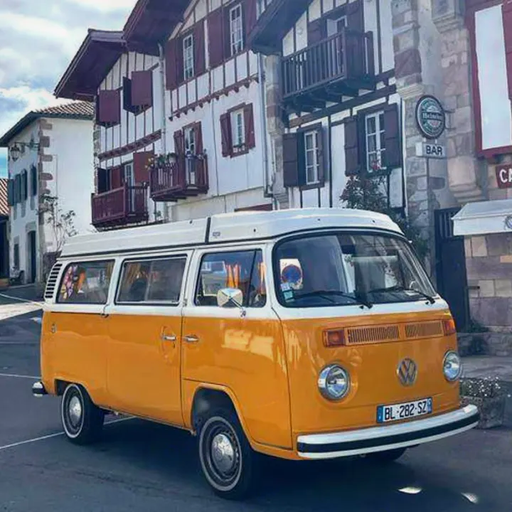 A cheerful yellow and white vintage VW campervan, an ideal RV rental, parked on a charming European street.. Volkswagen T2 Westfalia 1979