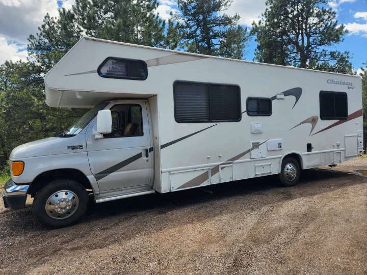 White Class C RV, a Ford E-450 Chateau Sport, parked on gravel for your next RV rental adventure.. Four Winds Chateau 2004